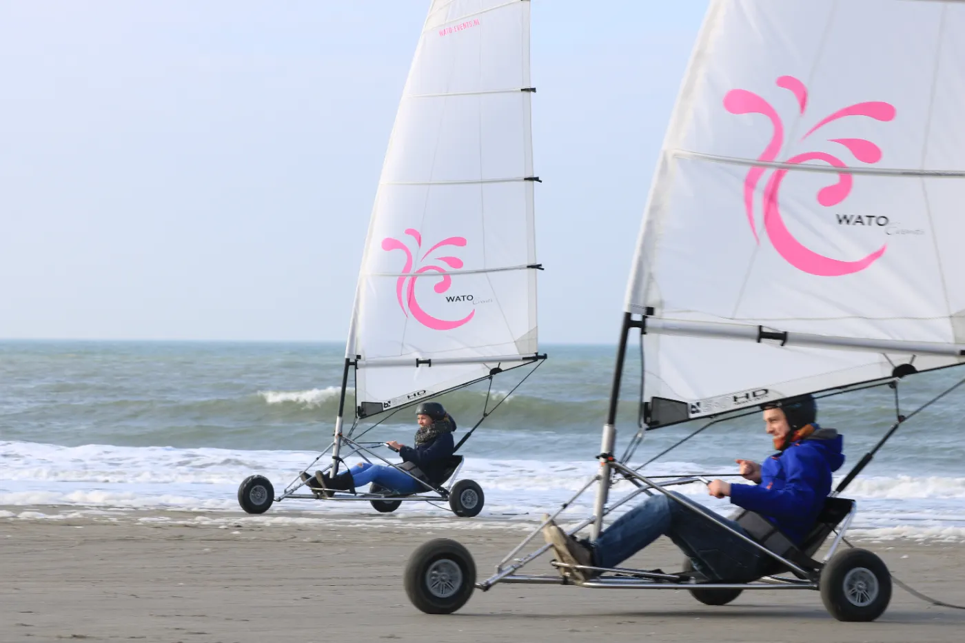 Twee blokarts met roze zeilen naast elkaar op het strand