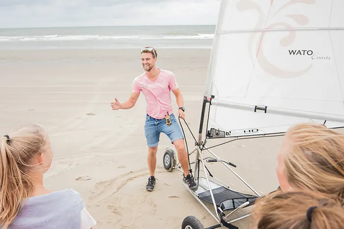 Instructeur legt het blowkarten uit aan een groep deelnemers op het strand